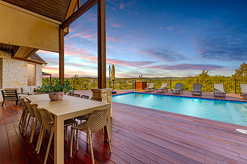 The patio of a vacation rental home in Dripping Springs, Texas showing a pool and outdoor dining table overlooking the Texas Hill Country.