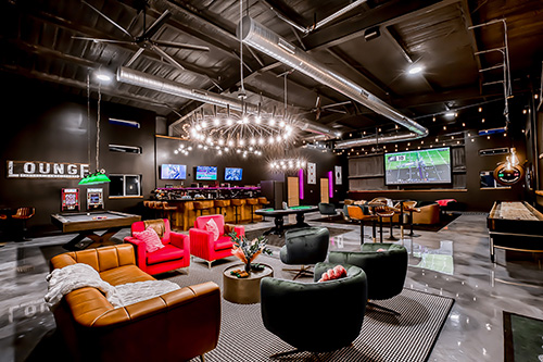 A spacious entertainment barn showing ample room and activities for large groups including a projector screen, bar, pool table, and comfortable seating.